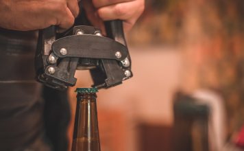 Close-up of beer bottle capping with capper machine.