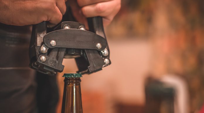 Close-up of beer bottle capping with capper machine.