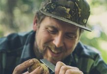 A man joyfully using a pocket knife in Australia to peel a mushroom during a nature hike, demonstrating the practicality of having a pocket knife while exploring the Australian wilderness.