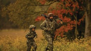 a person and a kid walking in a field with a bow