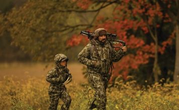 a person and a kid walking in a field with a bow